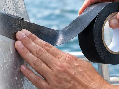 Hydro-Grip-Tape wird mit der Hand auf eine nasse Bootswand geklebt