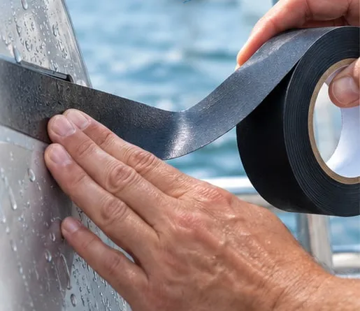 Hydro-Grip-Tape wird mit der Hand auf eine nasse Bootswand geklebt